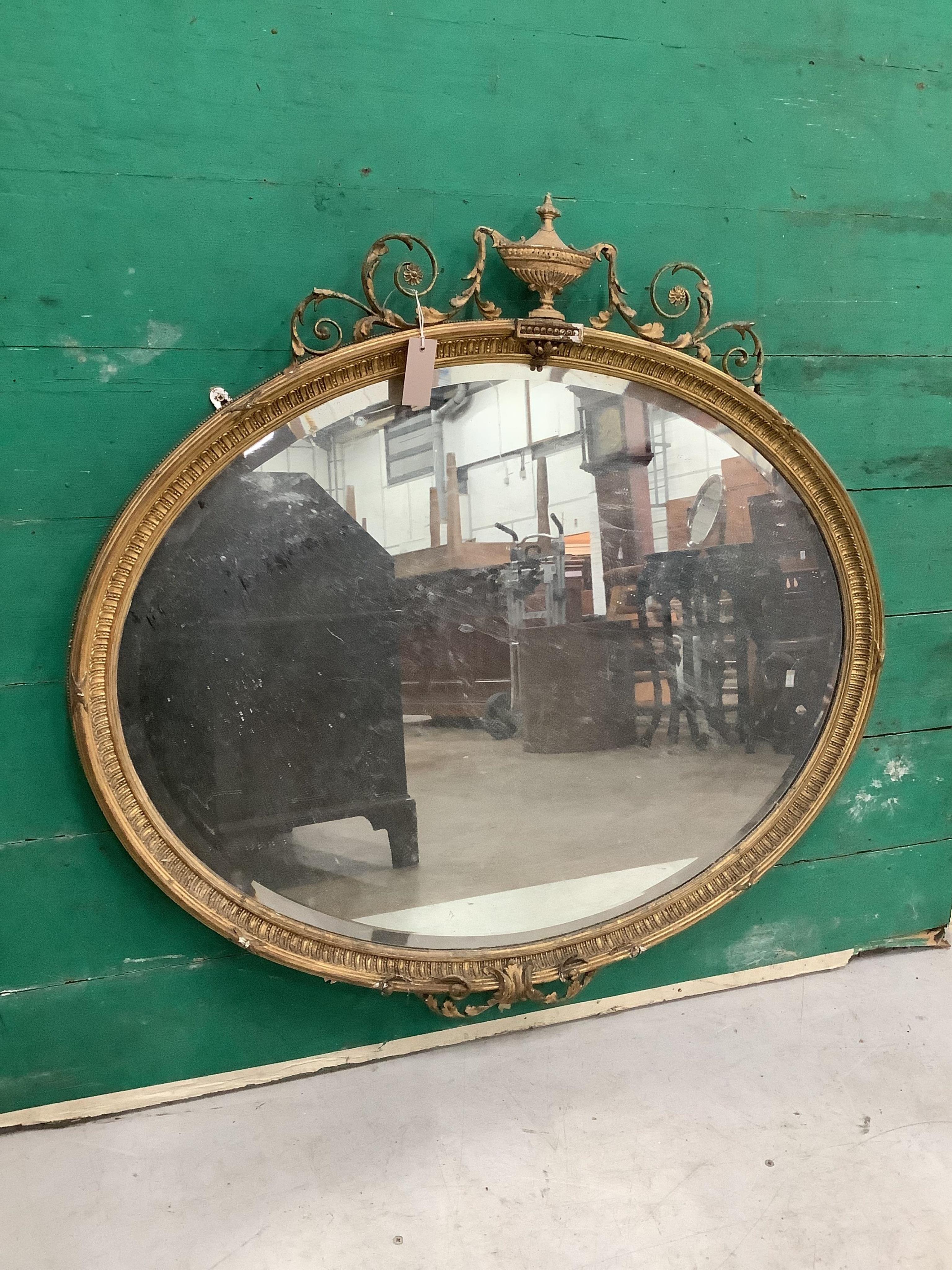 Two late Victorian / Edwardian Sheraton Revival oval giltwood and composition wall mirrors, larger width 100cm, height 95cm. Condition - poor to fair